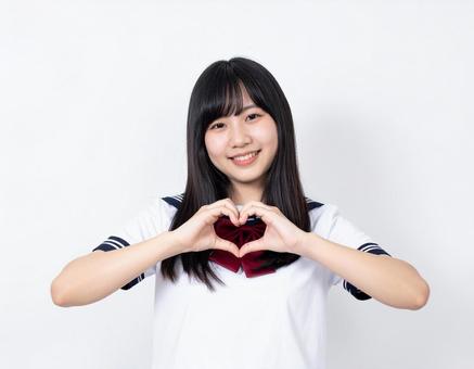 手でハートマークを作る女子生徒 手でハートマークを作る女子生徒の写真