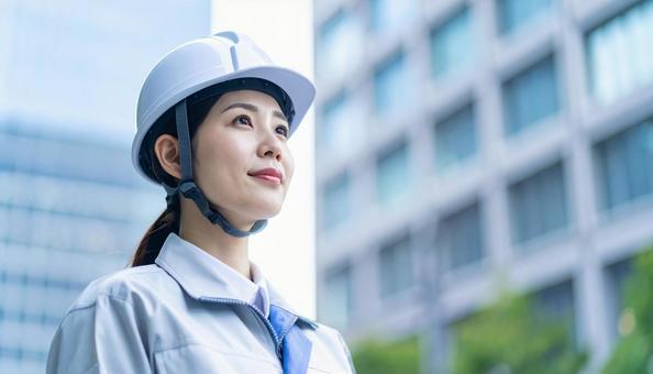 ビル背景に斜め上を見る若い女性建設作業員 ビル背景に斜め上を見る若い女性建設作業員の写真