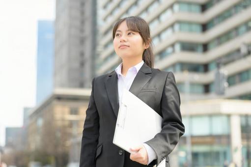 屋外でバインダーを持つスーツの女性 屋外でバインダーを持つスーツの女性の写真