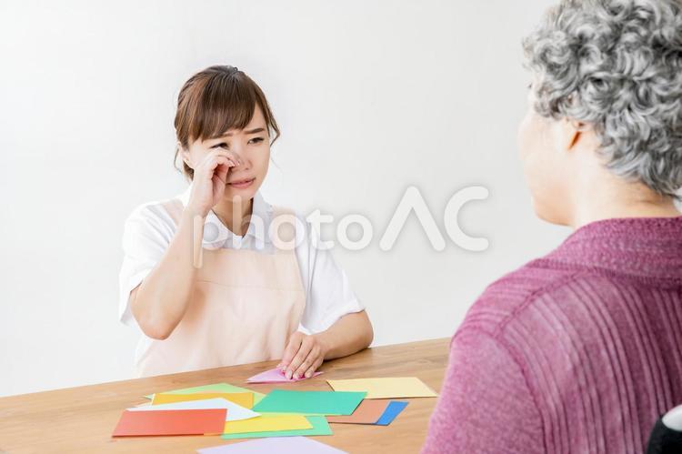 悲しい話をする高齢者の女性と介護士 老人ホーム,泣く,レクリエーションの写真素材