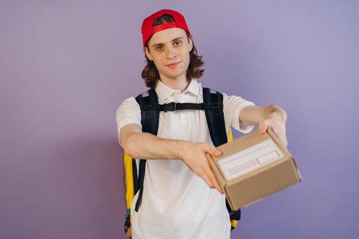 段ボール箱を差し出す配達員の男性 配達,フードデリバリー,デリバリーの写真素材