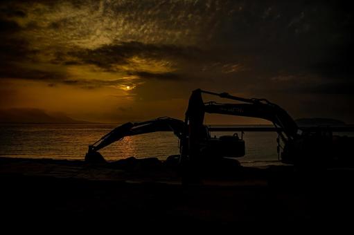 ＜素材＞夜明けの砂浜整地用のショベルカーの写真