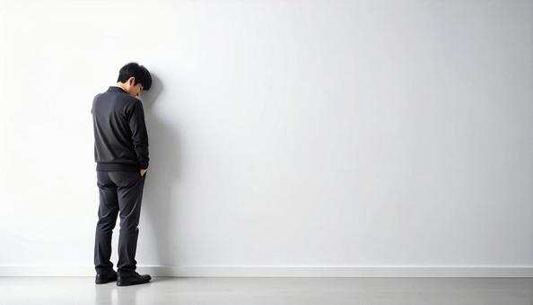 壁に寄りかかる落ち込んでいる日本人男性 壁に寄りかかる落ち込んでいる日本人男性の写真