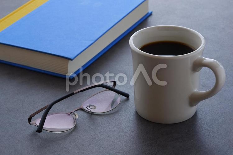 本とメガネ、コーヒーの入ったマグカップ 本,メガネ,テーブルの写真素材