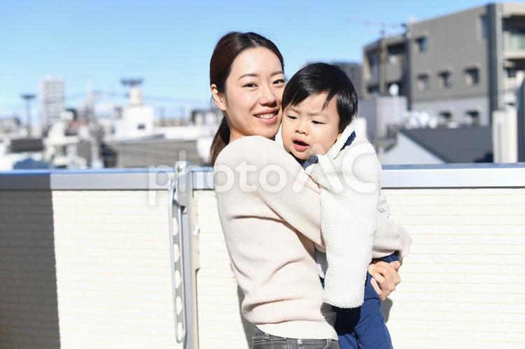 空と街並みを背景に子供を抱っこする母親 親子,子育て,抱っこの写真素材