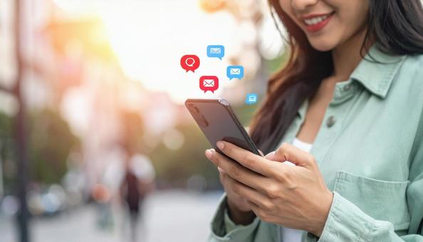 携帯電話でソーシャルメディアを楽しむ女性 携帯電話でソーシャルメディアを楽しむ女性の写真