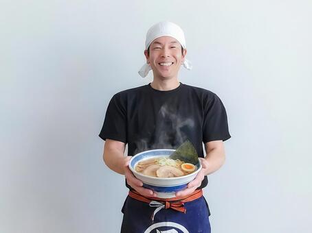 ラーメンを持つ笑顔の男性飲食店スタッフ 男性,ラーメン,料理の写真素材