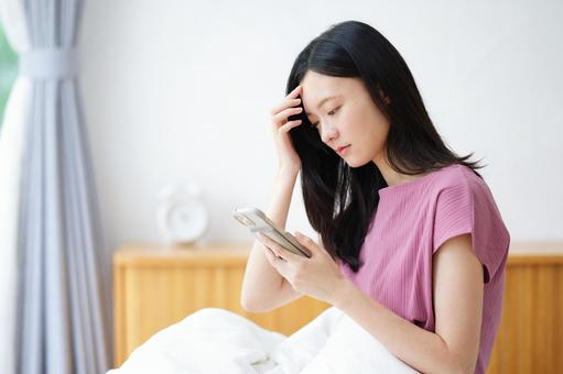 スマホを見て悩むロングヘアの女性 女性,スマートフォン,持つの写真素材