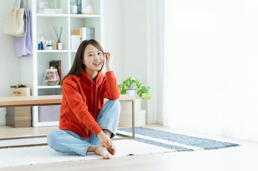 リビングでくつろぐ若い女性 リビングでくつろぐ若い女性 女性,笑顔,家の写真素材