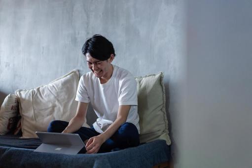 ベッドで在宅勤務をする若い男性 ベッドで在宅勤務をする若い男性 仕事,おしゃれ,家の写真素材