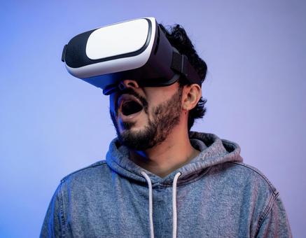 VRゴーグルを装着して驚く男性 VRゴーグルを装着して驚く男性の写真