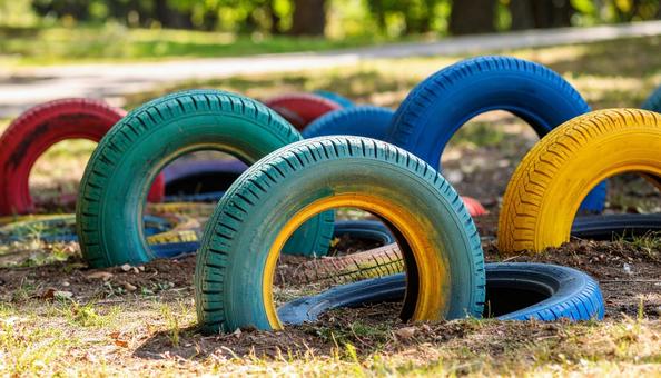 公園に遊べるように埋まるカラフルなタイヤの写真