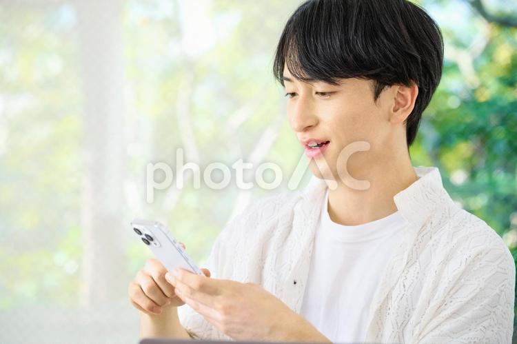 スマホを使う若い男性　リビング 男性,スマホ,くつろぐの写真素材