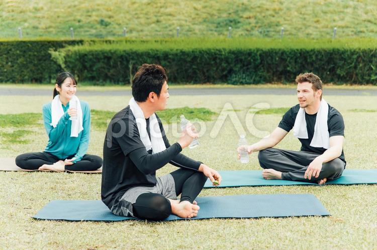 公園でヨガをしながら休憩する男女 ヨガ,パークヨガ,運動の写真素材