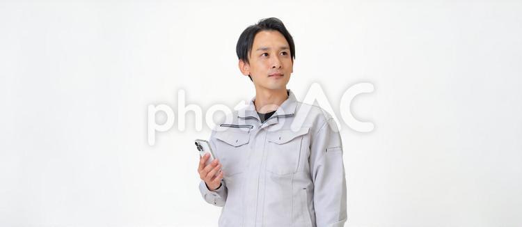 携帯を見る作業着を着た男性 日本人,点検,保守点検の写真素材