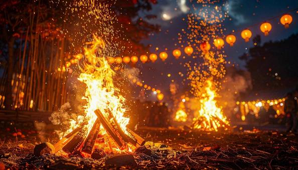 夜空を彩るどんど焼きと提灯の灯りの写真