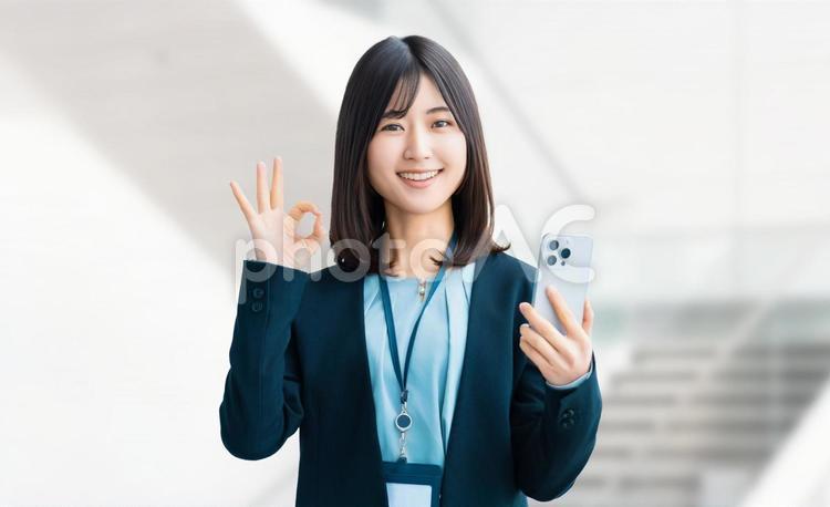 スマホを持ってOKポーズをする笑顔の女性 女性,ok,笑顔の写真素材