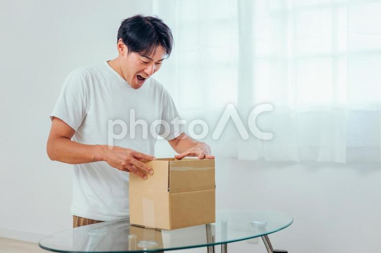 段ボールを開ける男性（喜ぶ） 荷造り,宅急便,宅配便の写真素材