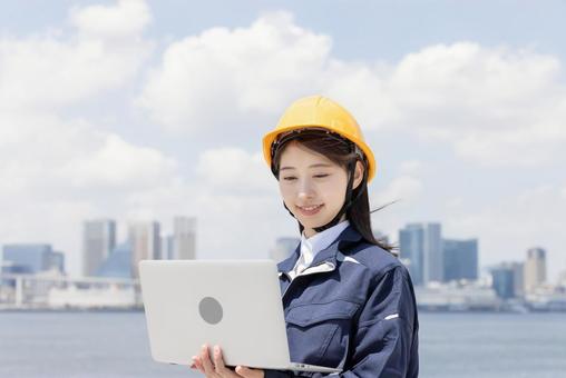 Young woman in work clothes using a laptop, JPG