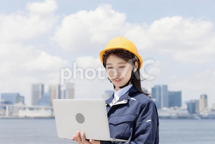ノートパソコンを使う作業服を着た若い女性 女性,人物,ビジネスウーマンの写真素材