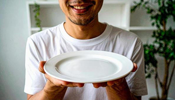 食後、空になったお皿を前に笑顔の男性 食後、空になったお皿を前に笑顔の男性の写真