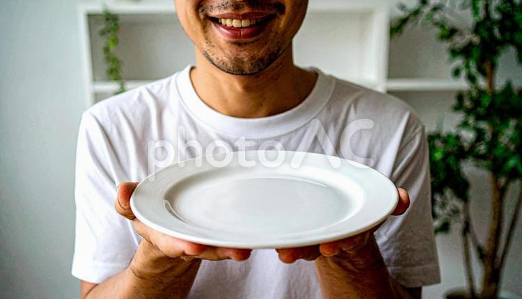 食後、空になったお皿を前に笑顔の男性 満腹,満足,食後の写真素材