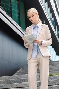 オフィスビルの外の階段でタブレットを見る ビジネスウーマン,ビジネス,女性の写真素材