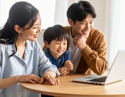 自宅のパソコンの画面を一緒に見る3人家族 自宅のパソコンの画面を一緒に見る3人家族の写真
