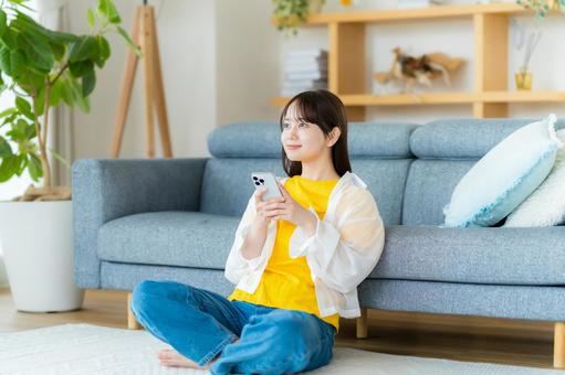 部屋でスマホを操作する若い女性 部屋でスマホを操作する若い女性 スマホ,若い女性,笑顔の写真素材