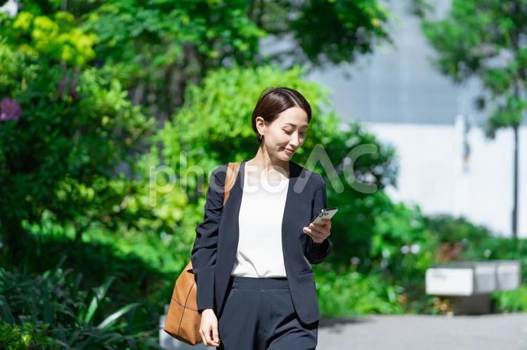 携帯を見るスーツを着た女性 スーツ,人物,会社員の写真素材