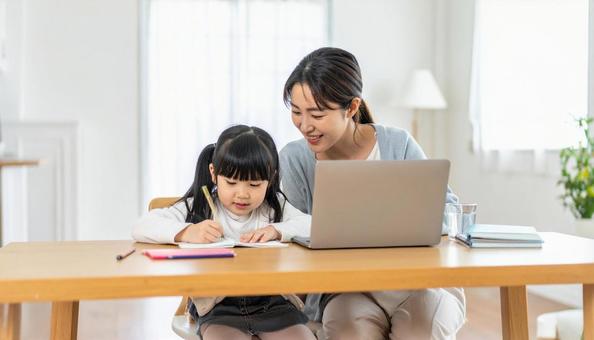  在宅勤務をする母親と勉強をしている娘の写真