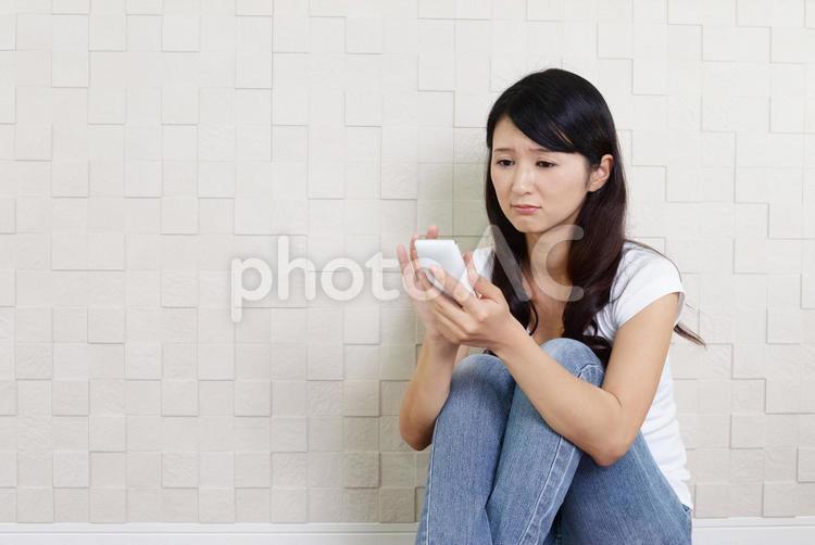 スマホを持っている困った表情の女性 女性,主婦,スマホの写真素材