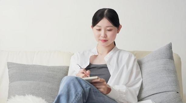 自宅でアイデアをメモするアジア人女性 自宅でアイデアをメモするアジア人女性 アイデア,メモ,考えるの写真素材