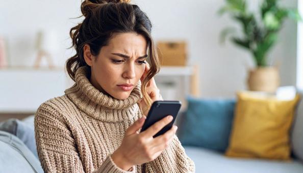 不安げに携帯電話を眺める外国人女性 不安げに携帯電話を眺める外国人女性の写真