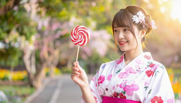 浴衣を着た女性が手に持つ飴を見る 浴衣を着た女性が手に持つ飴を見るの写真