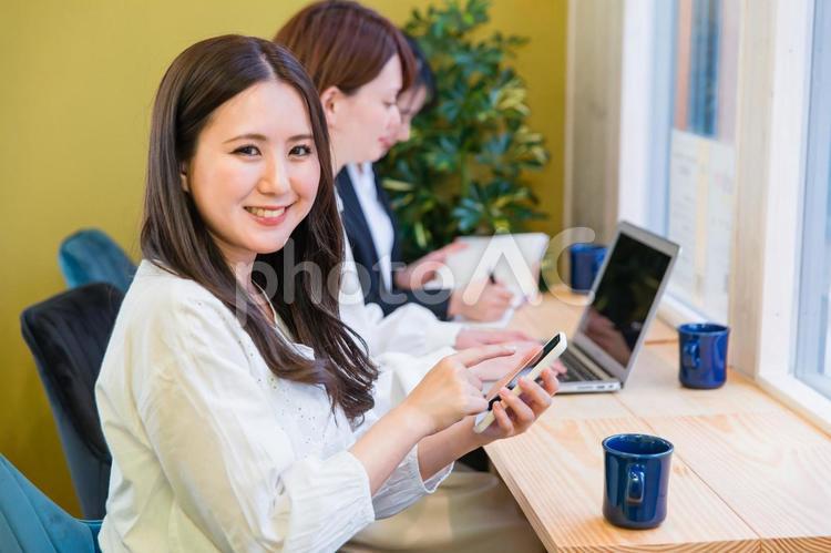 カフェの窓際カウンター席にいる女性（スマホを見る） スマートフォン,アプリ,スマホの写真素材