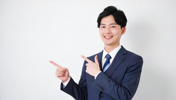 スーツ姿の若い男性・スペース指差し スーツ姿の若い男性・スペース指差しの写真
