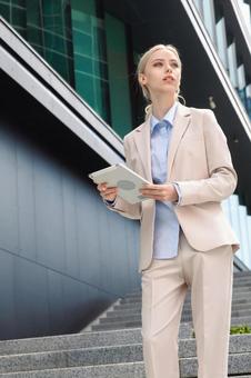 オフィスビルの外の階段でタブレットを持って立っているビジネスウーマン ビジネスウーマン,ビジネス,女性の写真素材