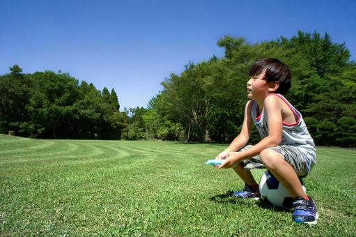 <素材>夏の公園でサッカーに疲れた男の子 <素材>夏の公園でサッカーに疲れた男の子の写真