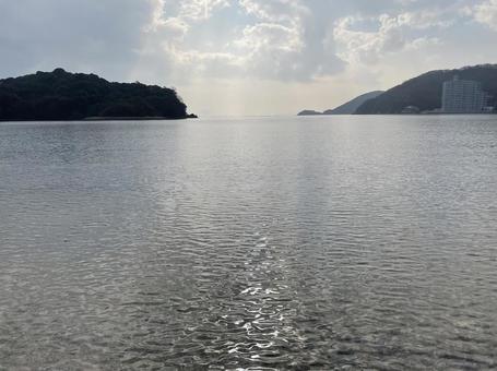 湾内に浮かぶ生島と陽の光の写真