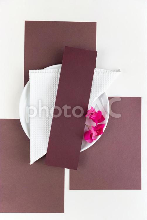 敷かれた茶色い紙と白いお皿に添えられたピンクの花と茶色いカード モックアップ,物撮り,テーブルコーディネートの写真素材