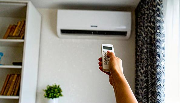 エアコンを操作するリモコンを持つ女性の手の写真