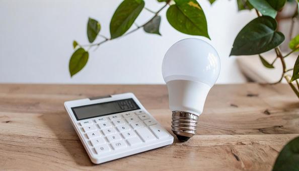 光熱費のイメージ 電球と白い計算機 光熱費のイメージ 電球と白い計算機の写真