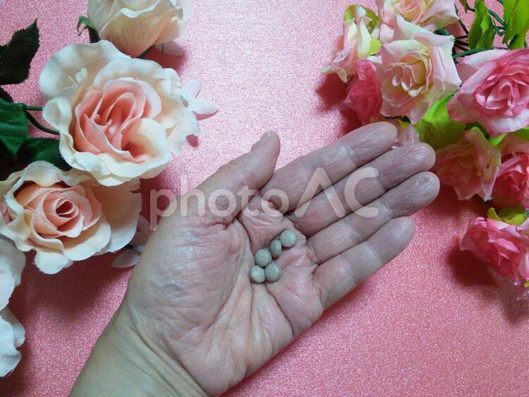 錠剤のサプリメントを 手のひらに乗せたところ  アンチエイジング,サプリメント,バラの写真素材