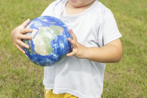 地球儀を持って草原で立っている男の子 男の子,地球,地球儀の写真素材