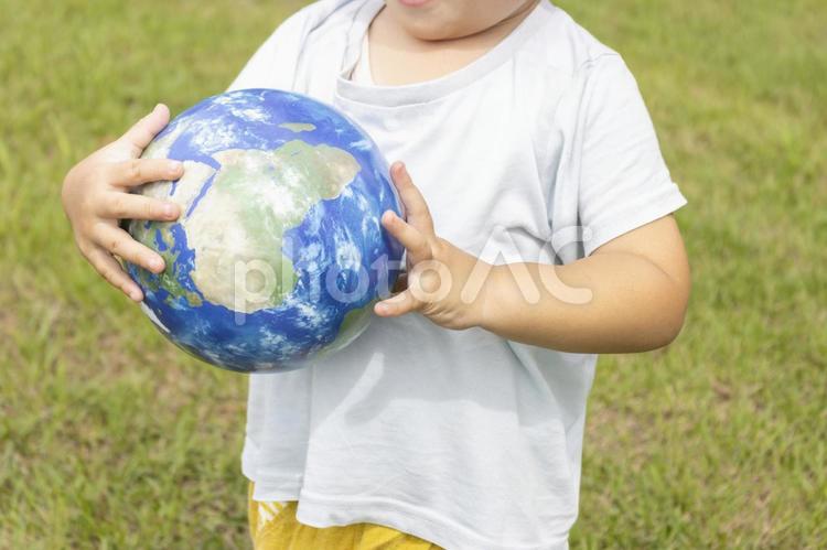 地球儀を持って草原で立っている男の子 男の子,地球,地球儀の写真素材