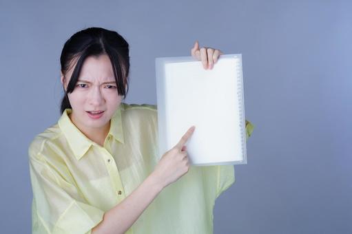 資料を見せて怒った顔をしている黄色い服の女性 女性,指差し,資料の写真素材