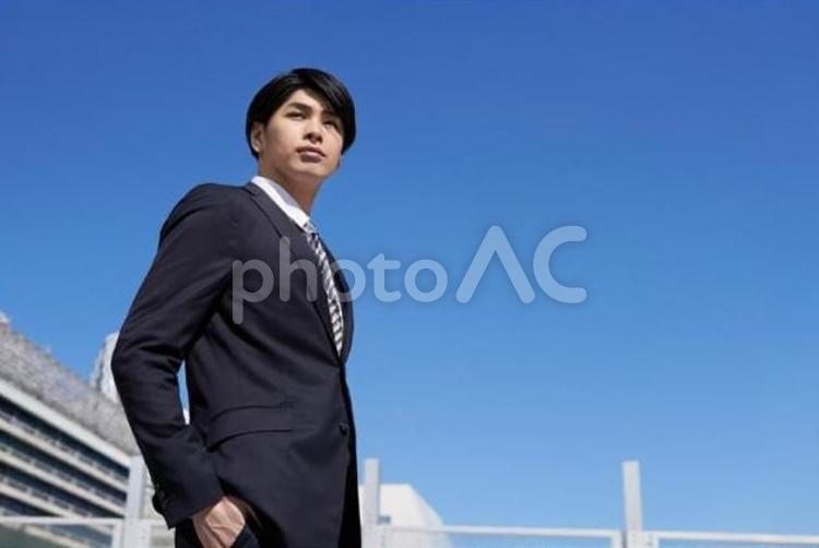 オフィス街に立つ日本人男性ビジネスマン	 ビジネスマン,青空,男性の写真素材