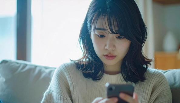 不安げにスマホを見る女性の写真
