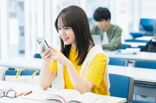 教室でスマホを見る女子大学生 スマホ,笑顔,大学生の写真素材